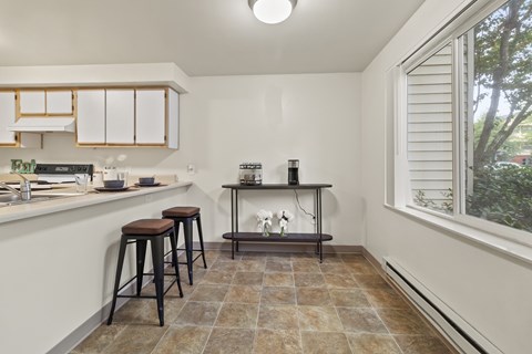 A kitchen with a bar stool and a table with a plant on it.