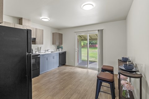 A kitchen with a black refrigerator and wooden floors.