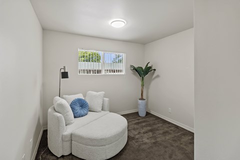 A white couch with a blue pillow is in a room with a window.