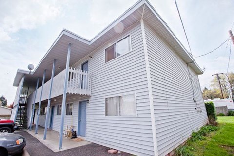 A two-story house with a grey siding exterior and a blue door.