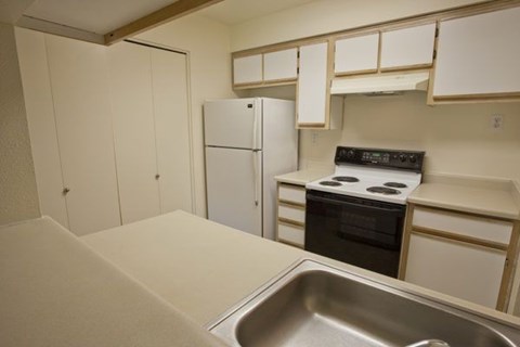 A kitchen with a stove, refrigerator, and sink.