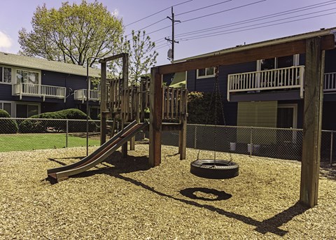 a playground with a slide and a tire in front of a building
