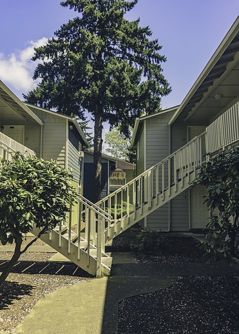 a building with stairs and a tree in front of it