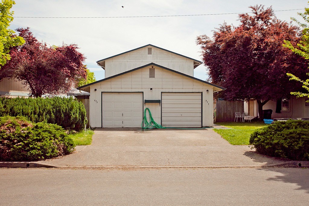 a white garage with a green hose on the door