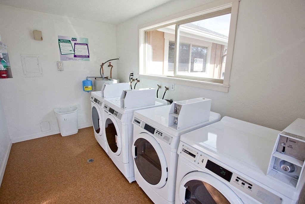 a washer and dryer room with four washing machines and a window
