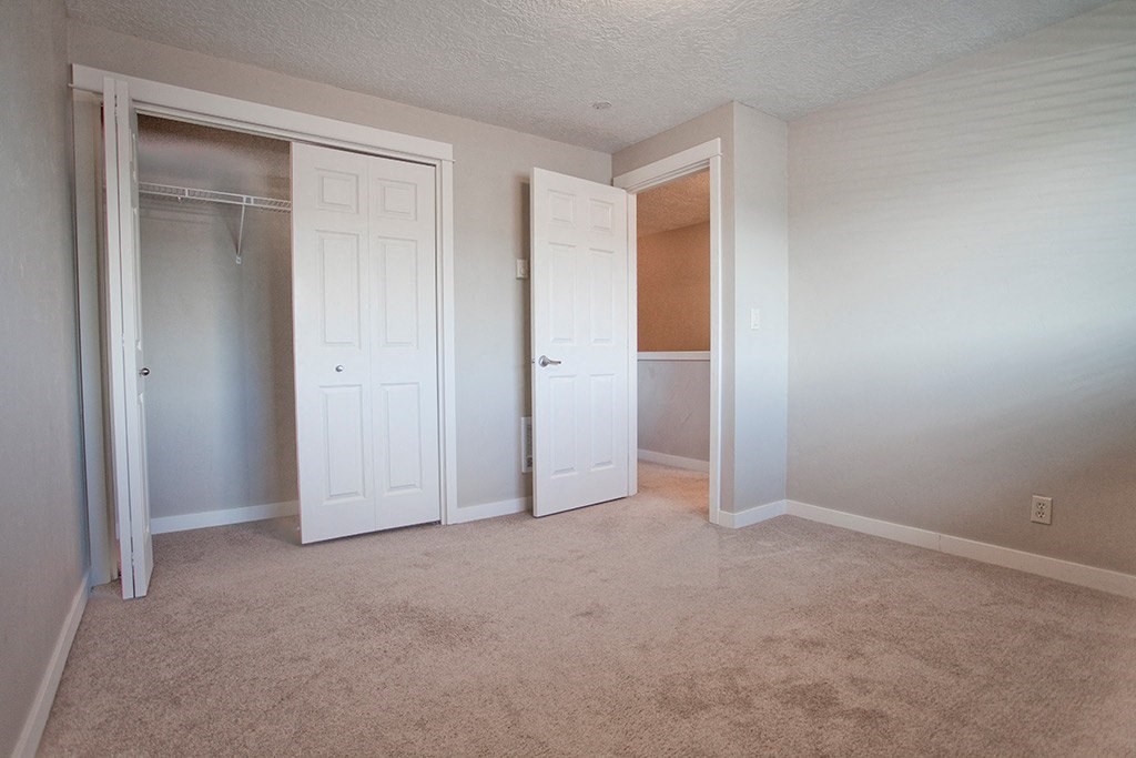 an empty bedroom with a closet and a mirrored closet door