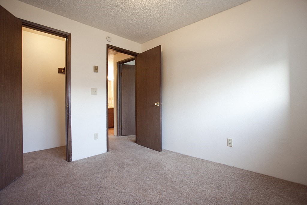 an empty living room with two doors and a door to a hallway