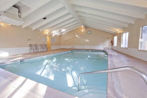 a swimming pool in a large room with chairs and a clock