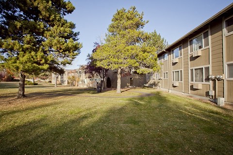 a view of the exterior of an apartment building with grass and trees