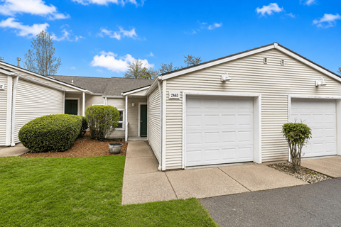A row of houses with garages and green lawns.