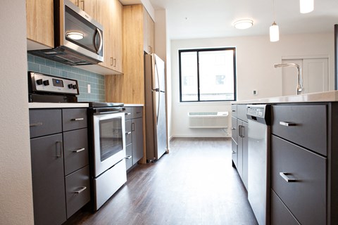 an empty kitchen with stainless steel appliances and a window