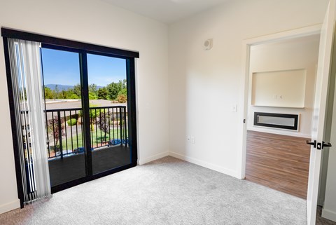 A room with a sliding glass door leading to a balcony.