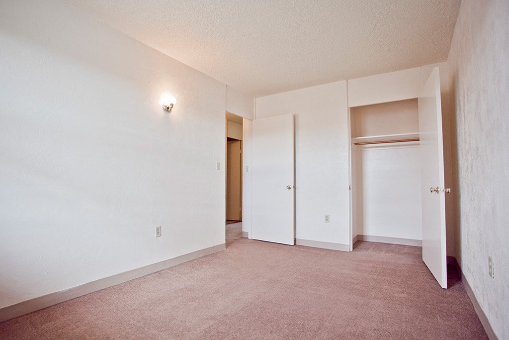 an empty living room with white walls and a closet