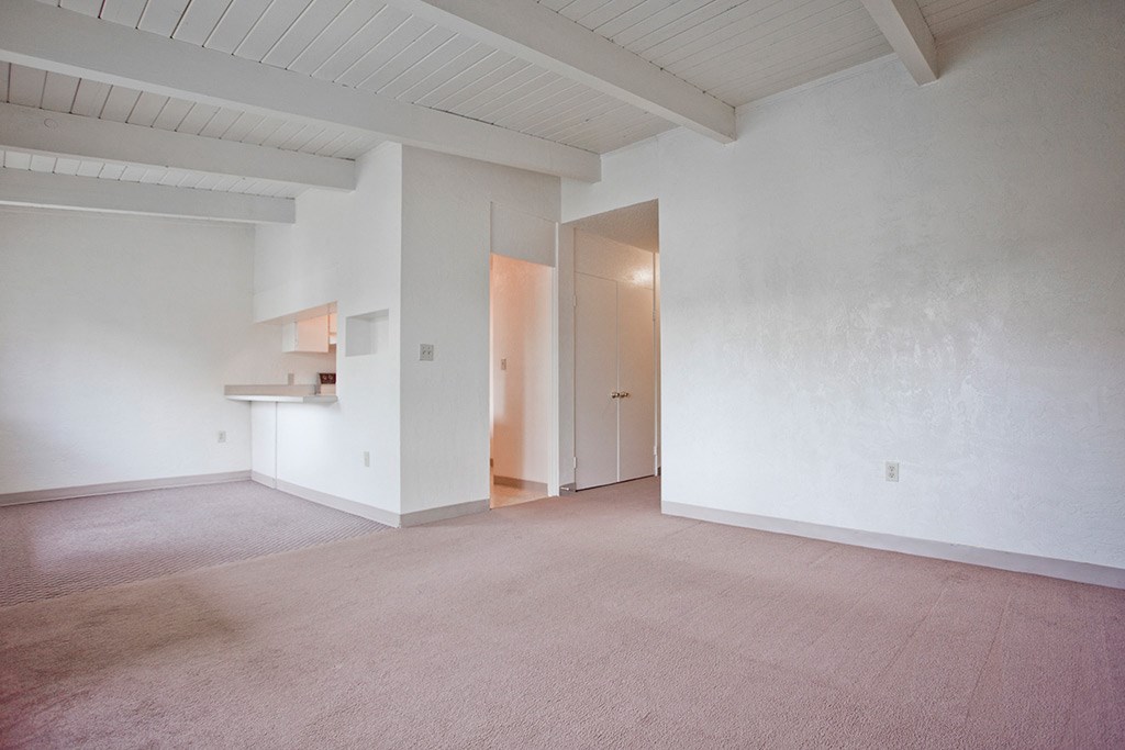 an empty living room with white walls and carpet
