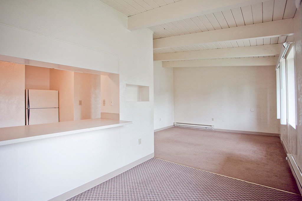 the living room and dining room of a house with white walls and a brown floor