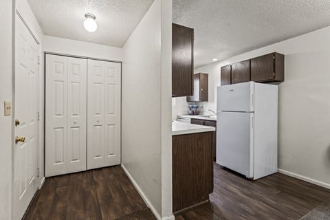 A kitchen area with a white refrigerator and brown cabinets.