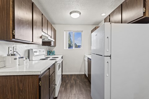A kitchen with white appliances and wooden cabinets.