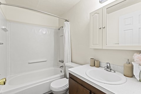 A white bathroom with a toilet, sink, and bathtub.