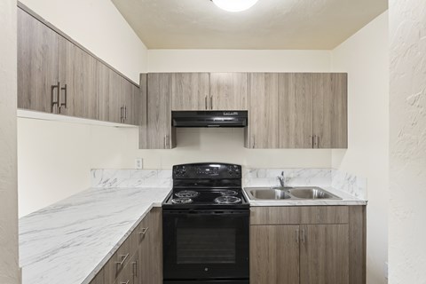 A kitchen with a black stove top oven and a marble counter top.