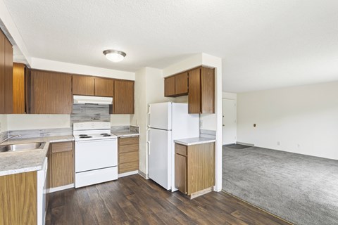 A kitchen with white appliances and wooden cabinets.