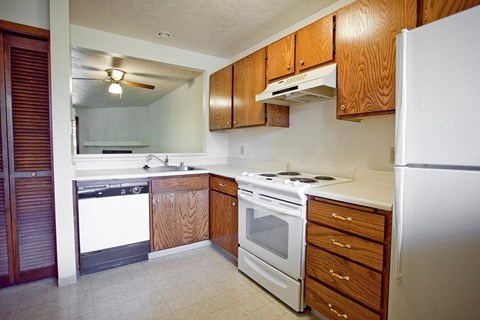 an empty kitchen with white appliances and wooden cabinets