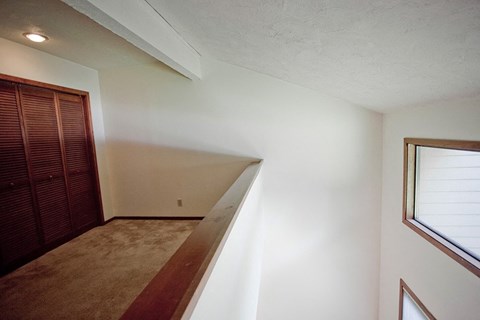 a room with a staircase and a window and a wooden closet