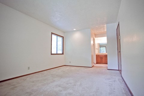 an empty living room with white walls and a door to a bathroom