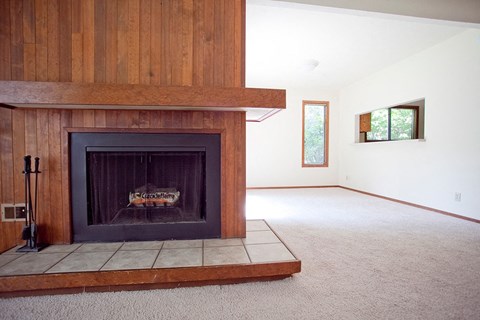 an empty living room with a fireplace with a wooden mantle