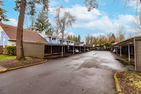 A parking lot with a few cars and a building in the background.