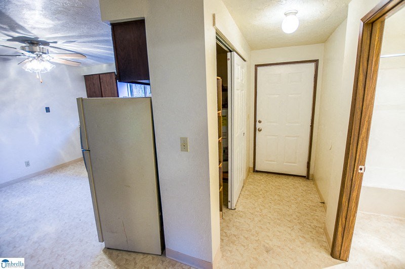 an empty living room with a refrigerator and a door to a closet