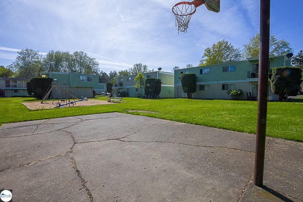a backyard with a basketball hoop in front of some apartments
