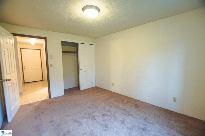 an empty living room with an open door to a bedroom