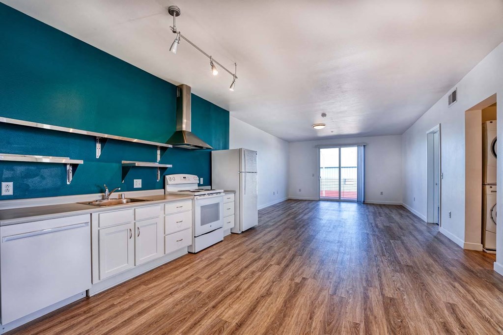 an empty kitchen and living room with a green wall and wood floors