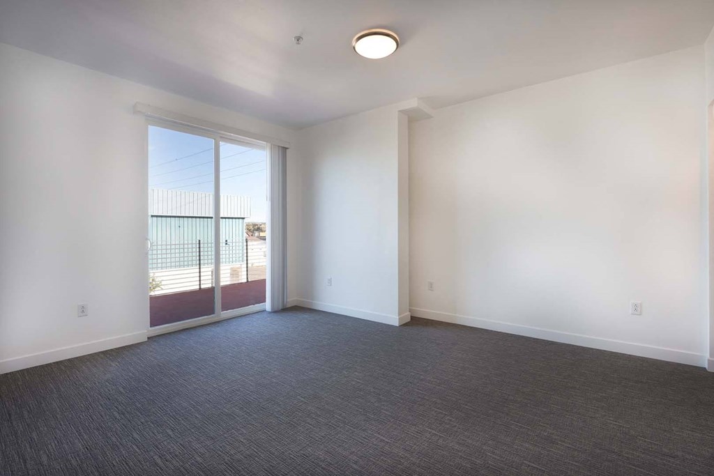 an empty living room with a door to a balcony