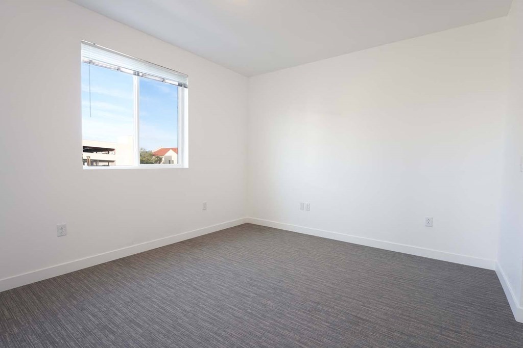 an empty room with a window and a carpet