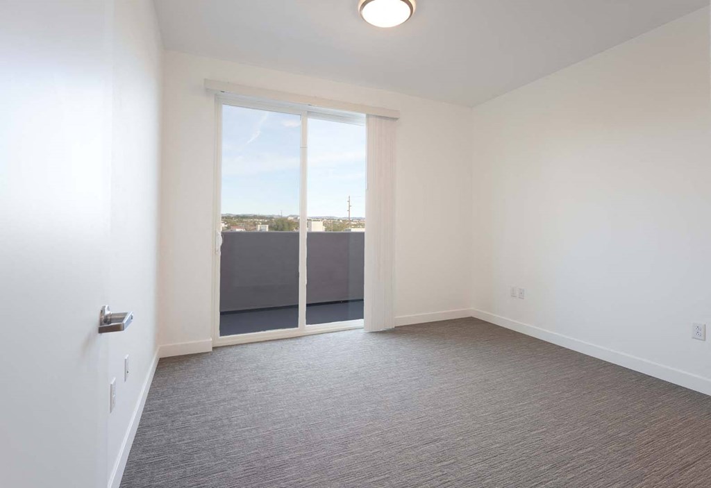 an empty living room with a door to a balcony