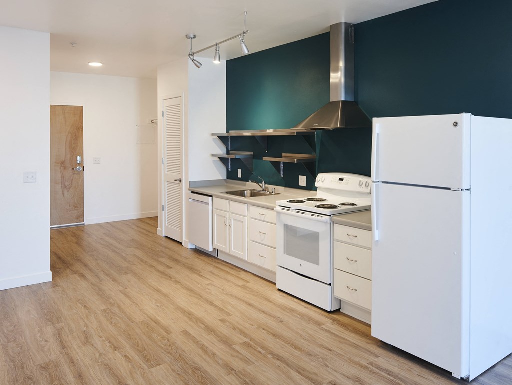 a kitchen with white appliances and a green wall and a white refrigerator