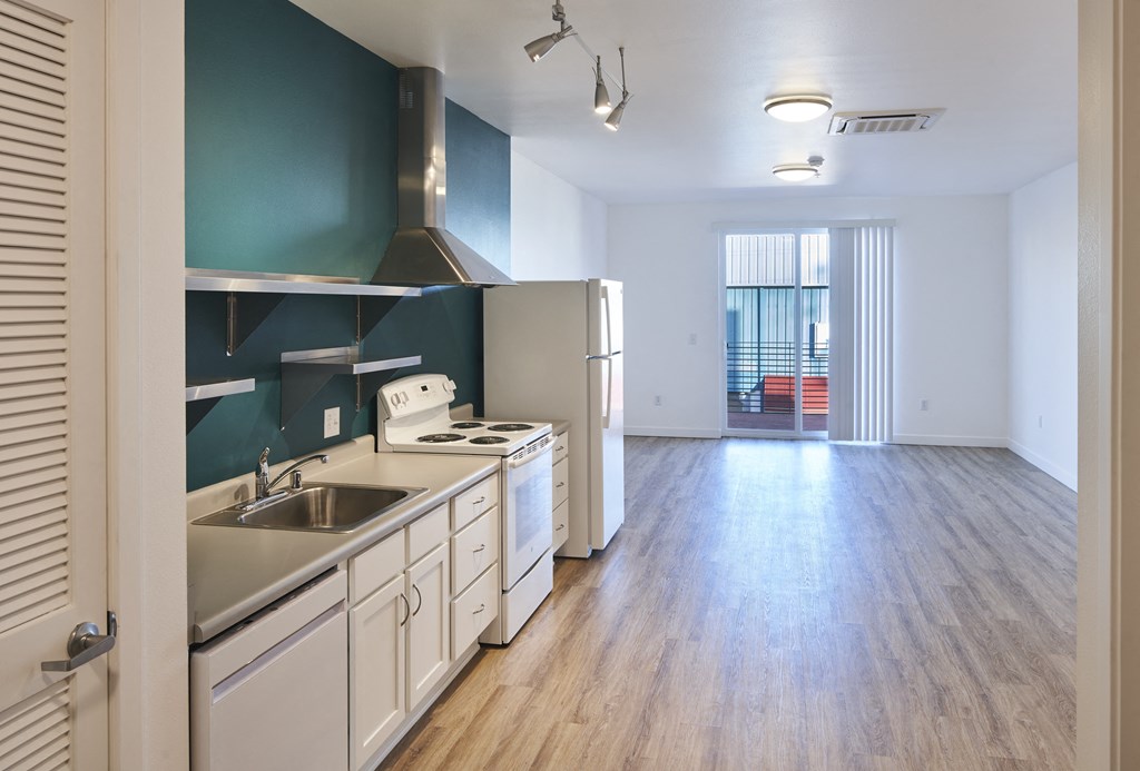 an empty kitchen and living room with a stove and a refrigerator