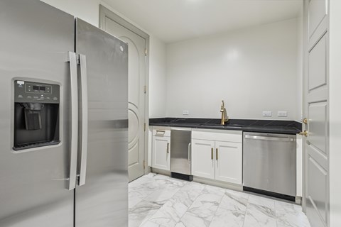 A kitchen with a stainless steel refrigerator and white cabinets.