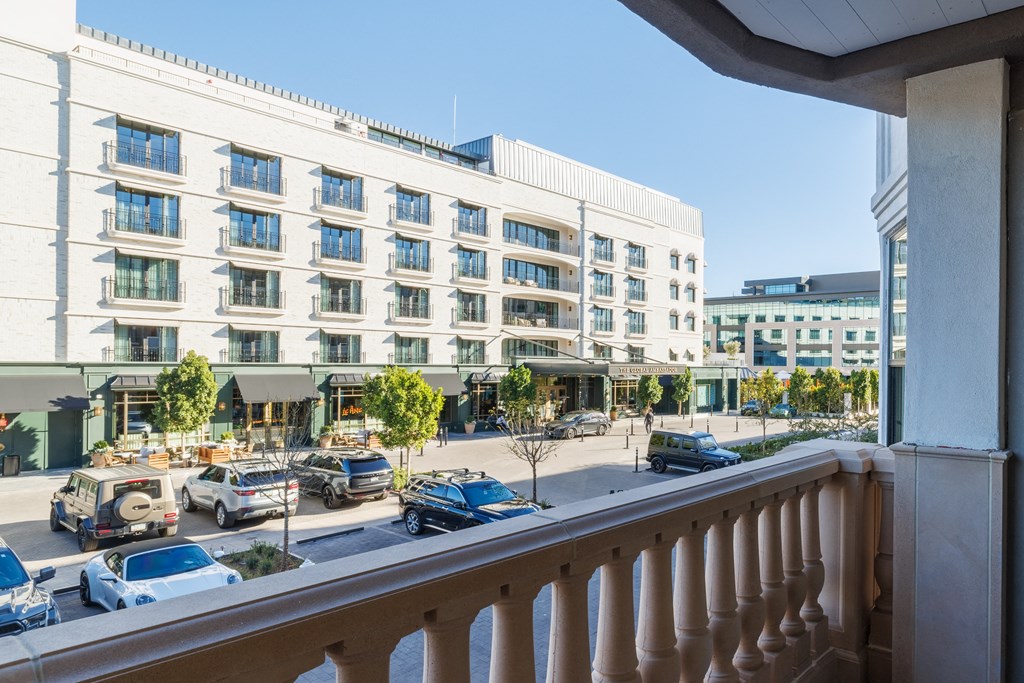 A white building with a balcony overlooking a parking lot.