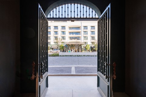 A view from inside a building looking out through an arched gate to a courtyard.