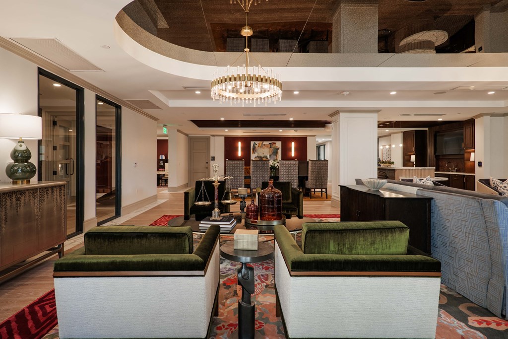 A large, modern living room with a green couch and a chandelier.