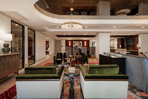 A large, modern living room with a green couch and a chandelier.