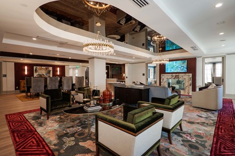 A large room with a chandelier and a rug with a pattern of red and black.