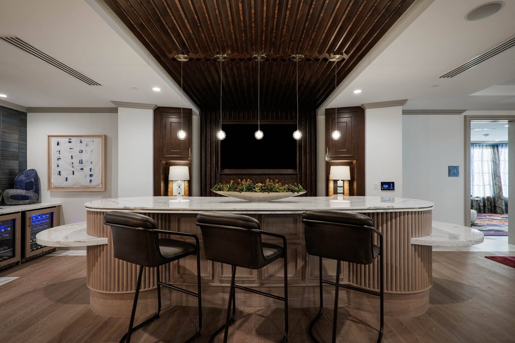 A modern kitchen with a wooden ceiling and bar stools.