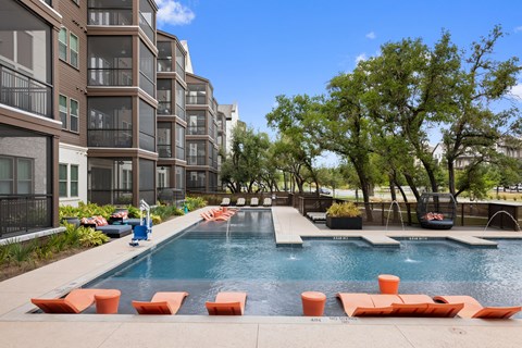 Pool with orange sun loungers and tree in background