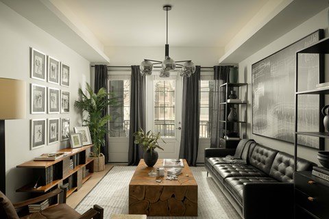 A modern living room with a black leather sofa and a wooden coffee table.