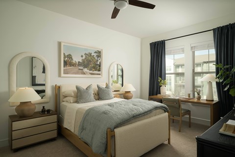 A bedroom with a large bed, a painting on the wall, and a ceiling fan.