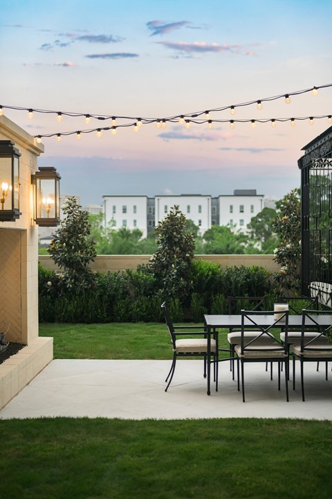 A patio with a table and chairs is set up with string lights above it.