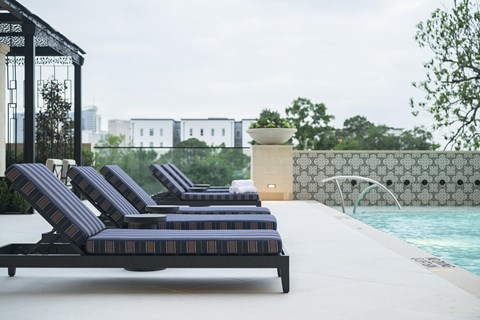 A poolside lounge area with striped sun loungers.